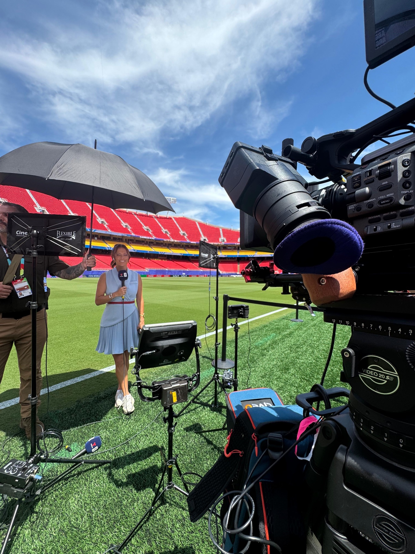 Reporter on field with broadcast camera at stadium